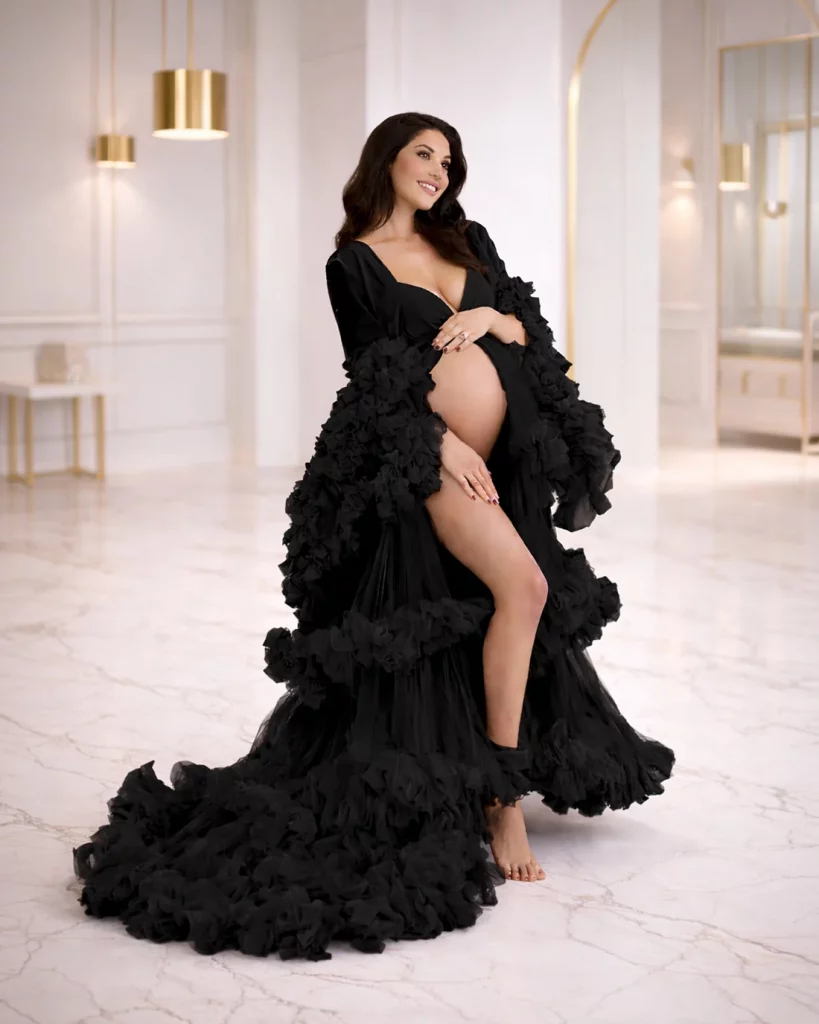pregnant woman wearing black ruffle maternity gown during studio maternity photoshoot