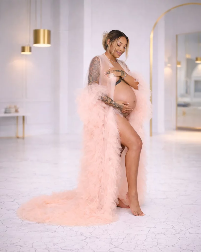 pregnant woman wearing blush ruffle maternity gown in luxury maternity photoshoot studio