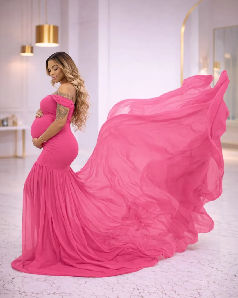 pregnant woman wearing flowing hot pink maternity gown with long dramatic train