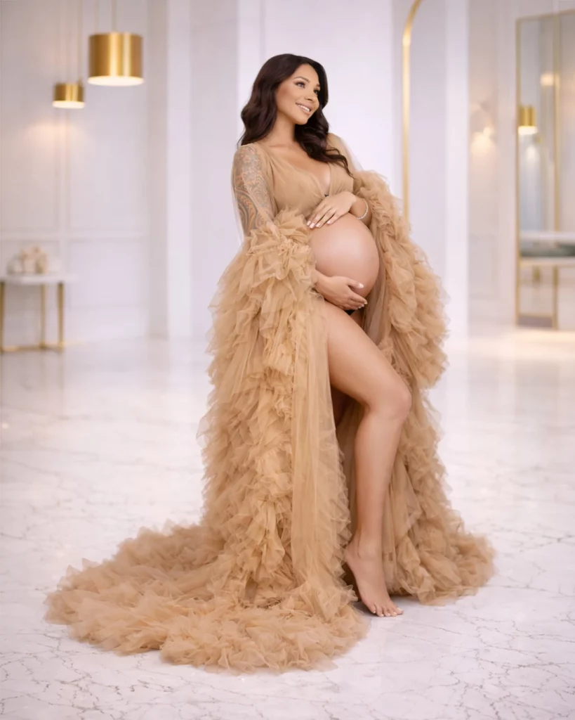 pregnant woman wearing nude tulle maternity gown during studio maternity photoshoot