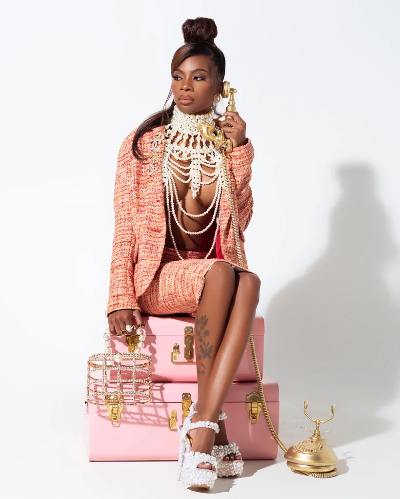 Fashion entrepreneur styled with pink luggage pearls and a vintage telephone for a campaign portrait