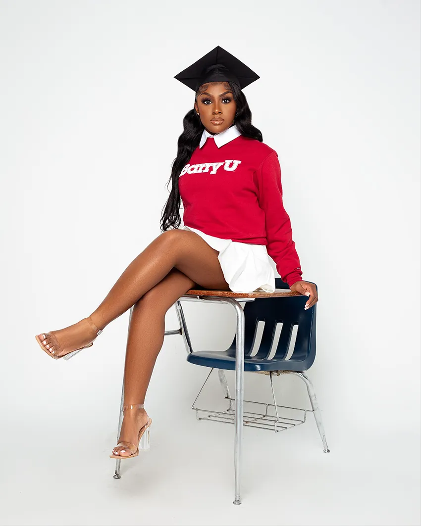 Female graduate seated at classroom desk in school colors