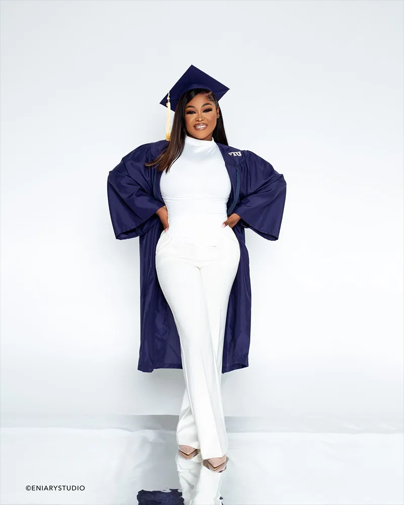 Female graduate in navy cap and gown with white outfit
